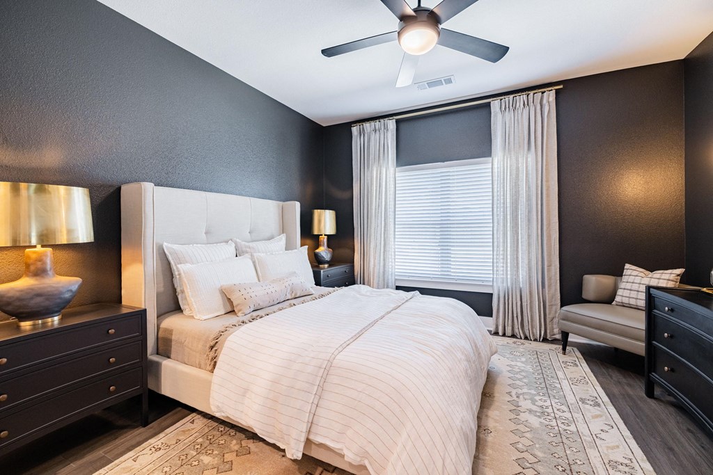 the master bedroom has a large bed and a ceiling fan