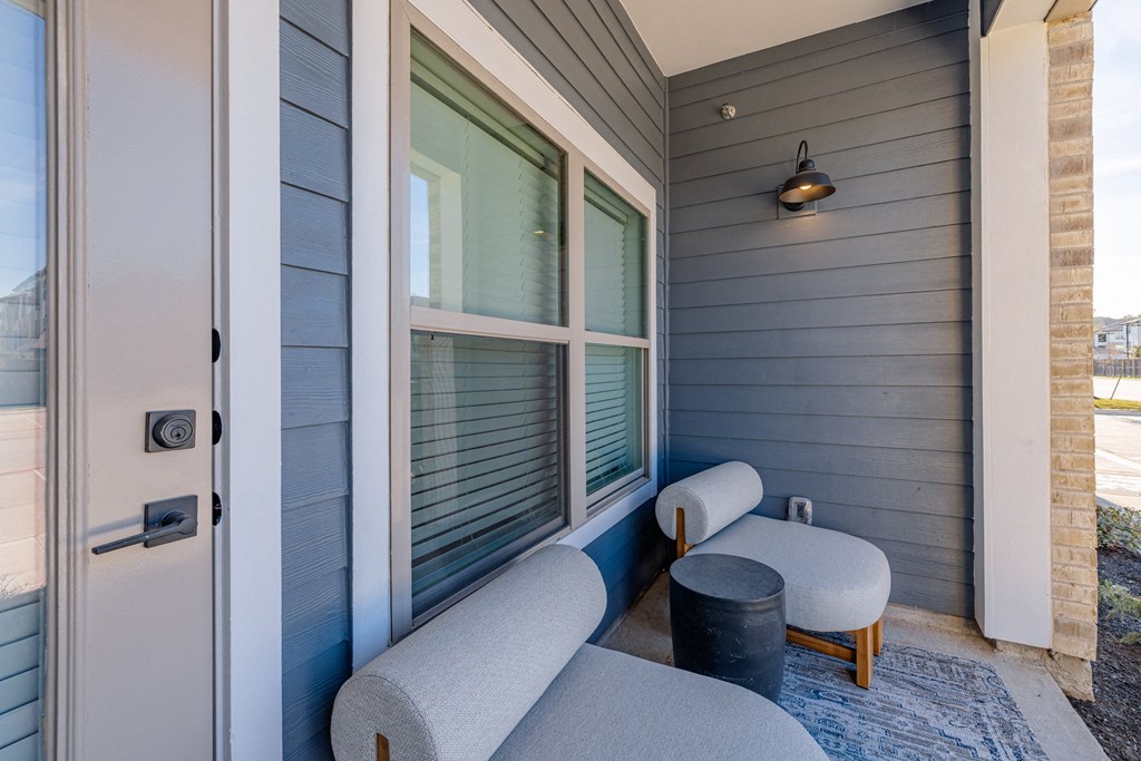 a small porch with two couches and a stool and a window