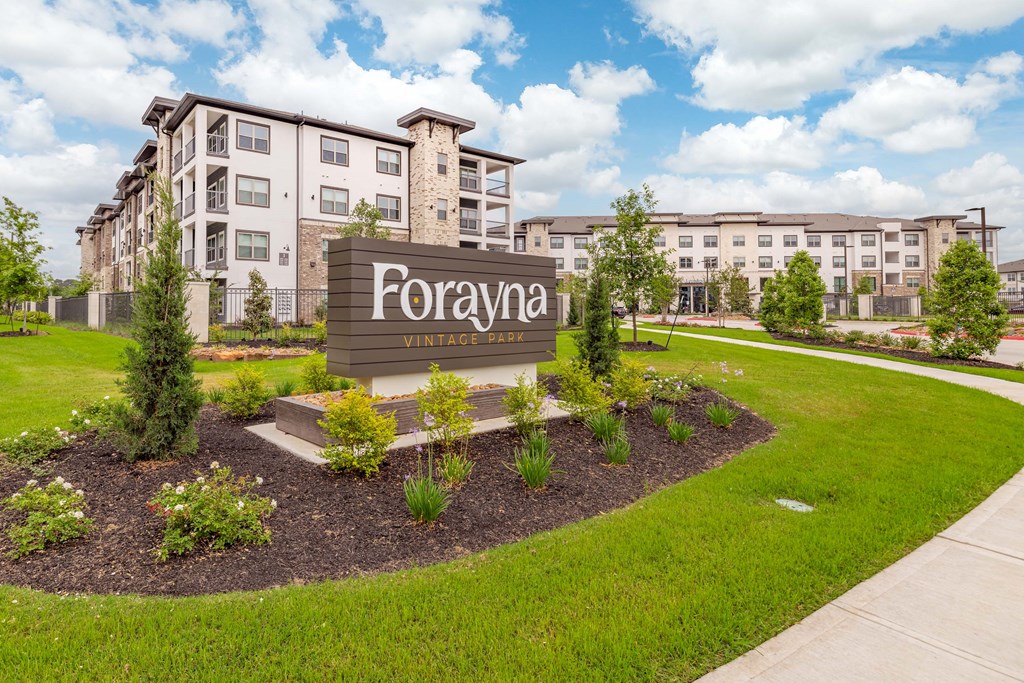 an apartment building with a for rent sign in front of a lawn