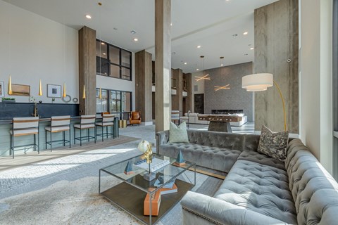 A modern living room with a grey sofa and a glass coffee table.