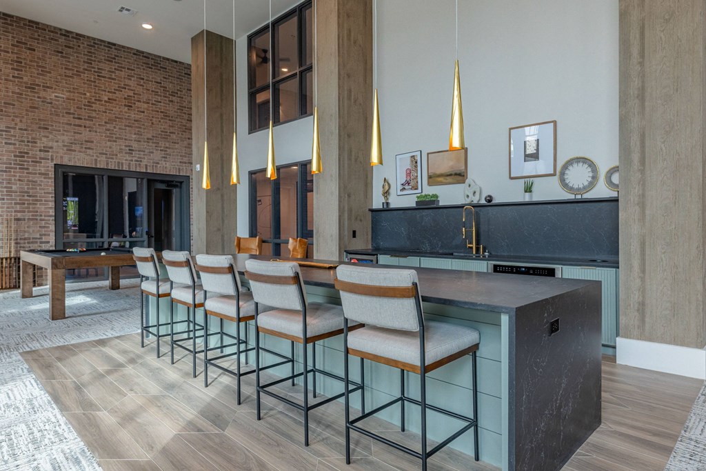a kitchen with bar stools in front of a long counter with chairs