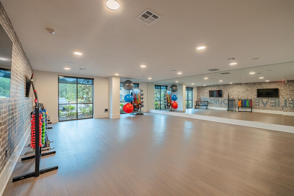 a large living room with a fireplace and a workout room with weights and yoga equipment
