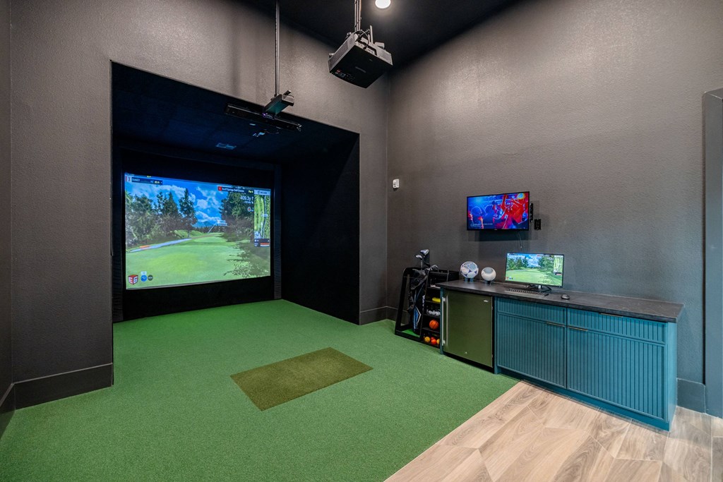 a game room with a large screen tv and a green carpet