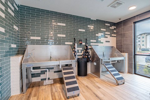 A kitchen with a stainless steel sink and a black trash can.