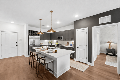A modern kitchen with a white island and dark wood floors.