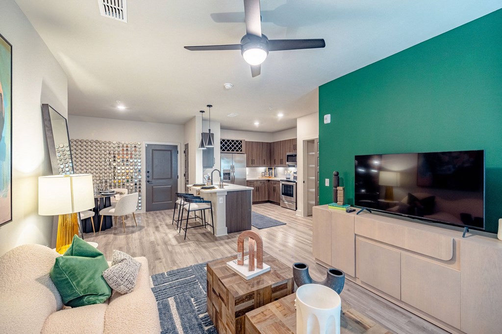 a living room with a green accent wall and a kitchen