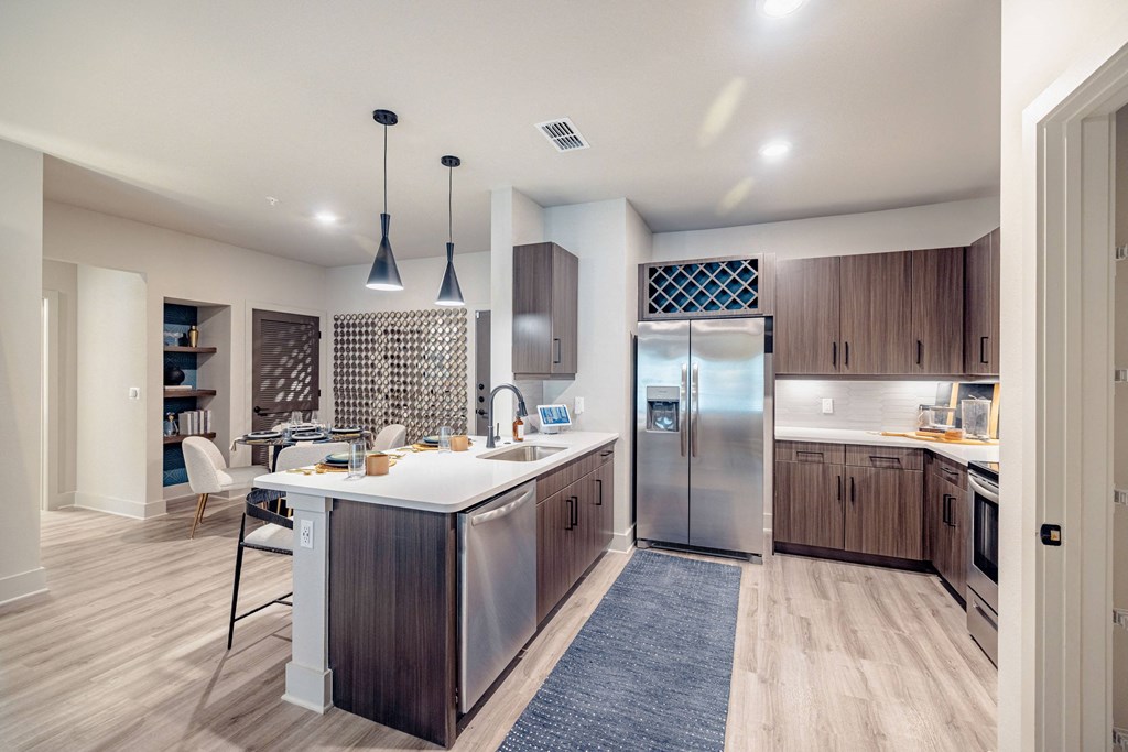 a kitchen with a large island and stainless steel refrigerator