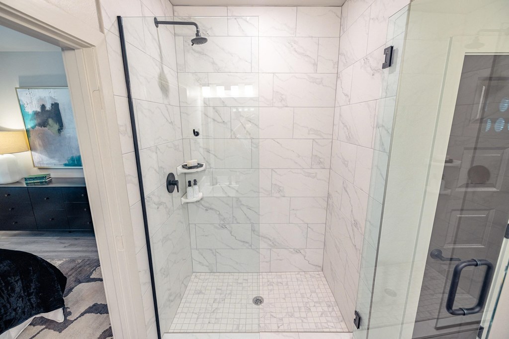 a large shower with white marble tile in a bathroom