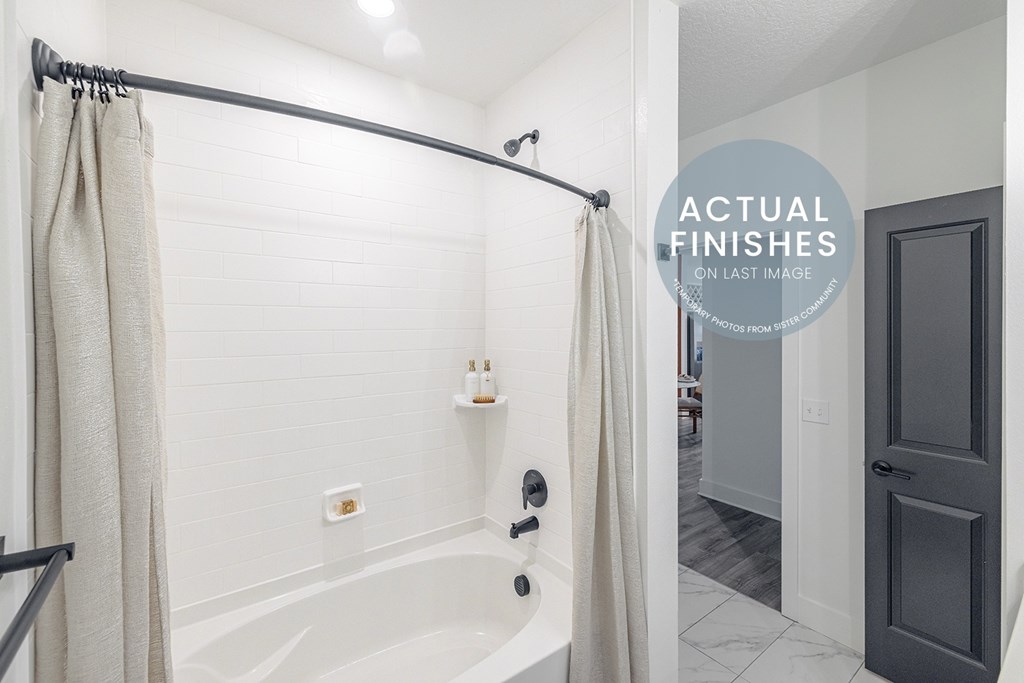 A bathroom with a white tub and a grey door.