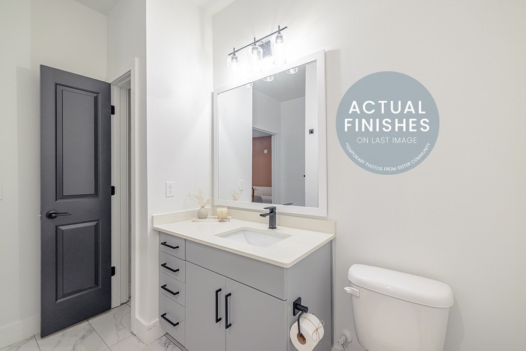 A bathroom with a sink, toilet and a mirror.