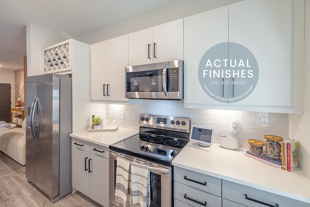 A modern kitchen with a stainless steel refrigerator, microwave, and oven.