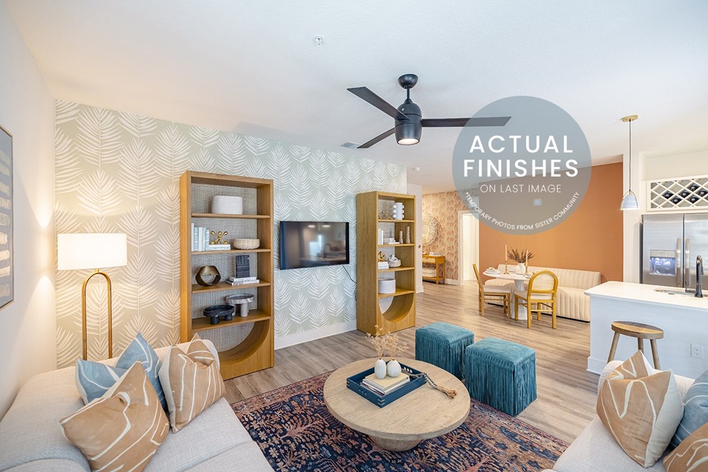 A living room with a grey sofa, a coffee table, and a patterned wallpaper.