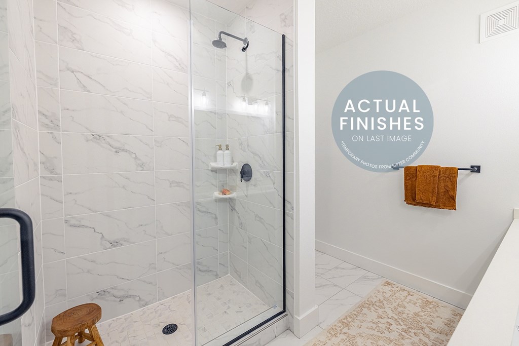 A bathroom with a marble wall and a glass shower stall.