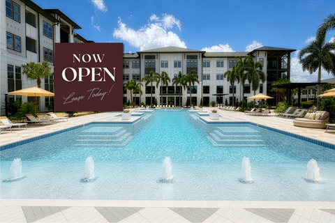A large pool with a sign that says "NOW OPEN" in front of a building.