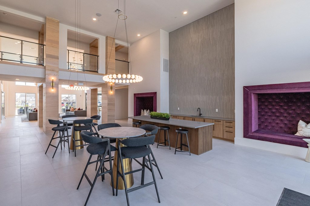 a dining area with tables and chairs and a kitchen with a purple couch