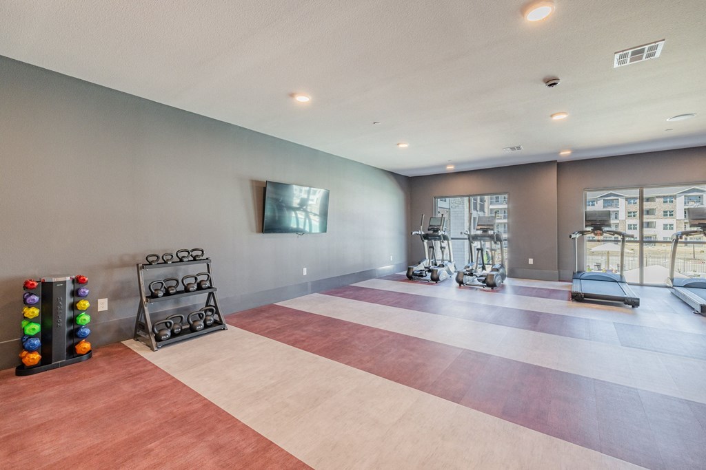 a workout room with weights and a tv on the wall