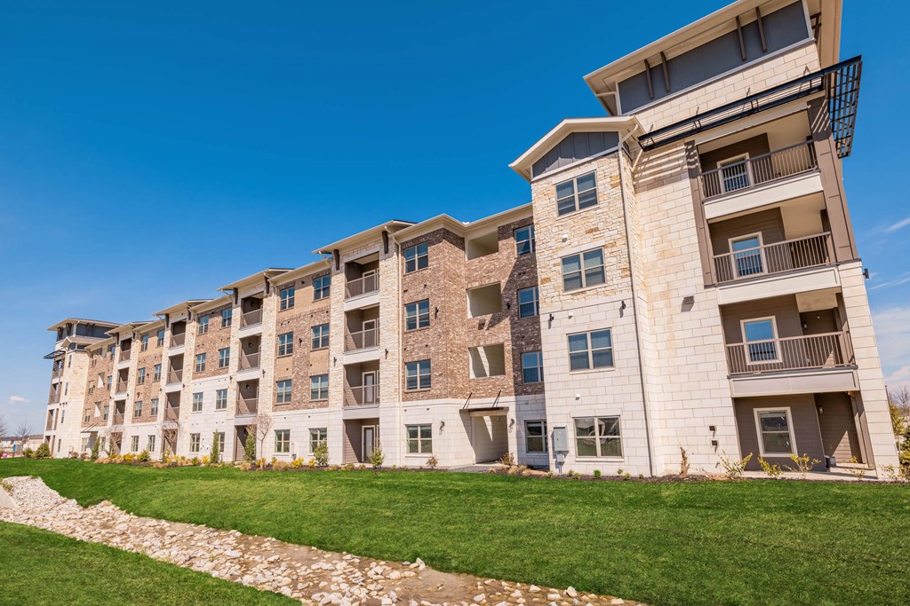 an apartment building with a green lawn in front of it