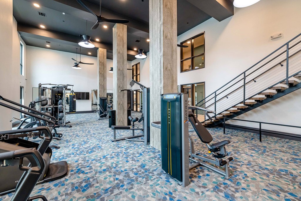 a gym with weights and cardio equipment and stairs