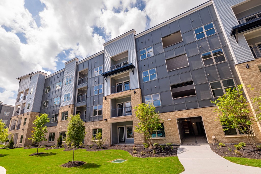 exterior of an apartment building with green grass and trees