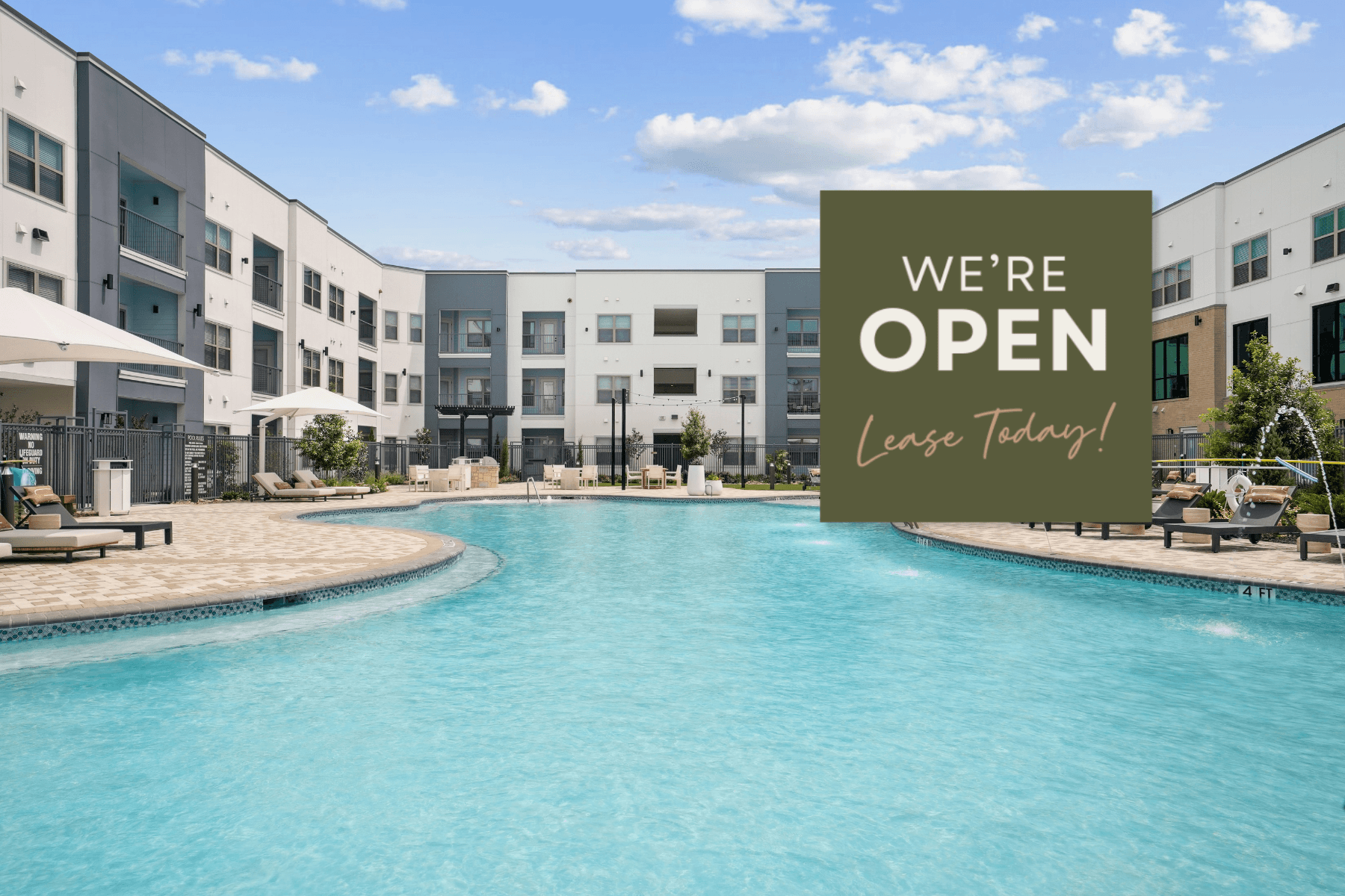 A pool in front of apartment buildings with a sign that says "We're Open Lease Today!"