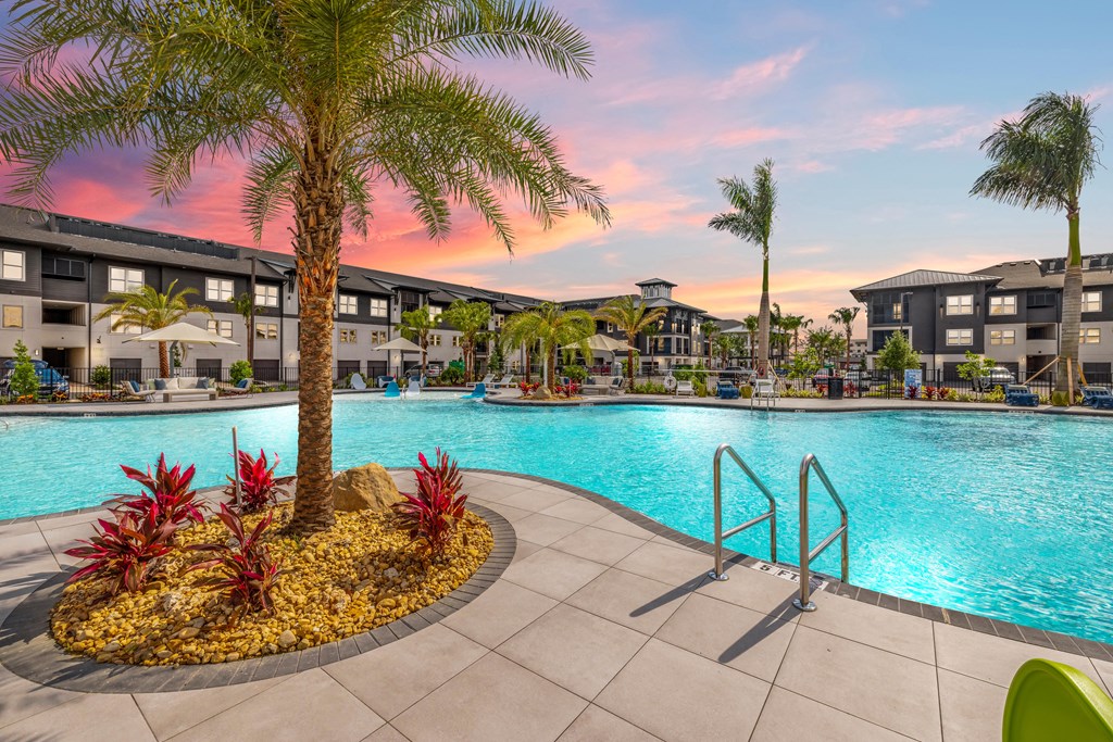 a swimming pool with palm trees and buildings in the background