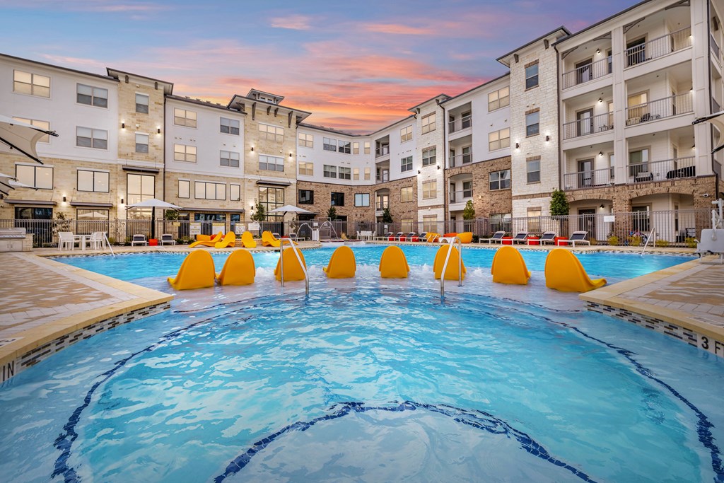 a large swimming pool with yellow rafts in front of apartment buildings
