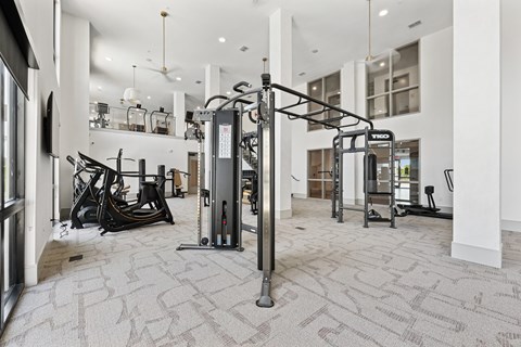 A gym with a variety of equipment including a treadmill, a stationary bike, and a rowing machine.