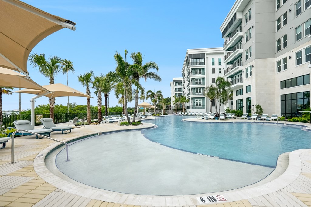 A large outdoor pool surrounded by palm trees and lounge chairs.
