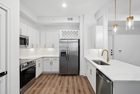 A modern kitchen with white cabinets and a wooden floor.