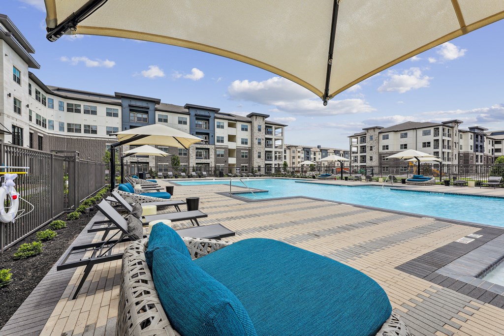 a large swimming pool with lounge chairs and umbrellas