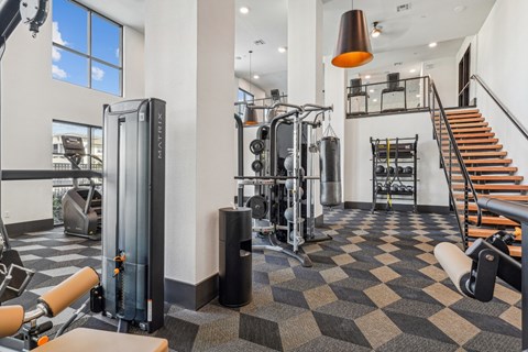 A gym with a variety of equipment including a treadmill, weights, and a staircase.