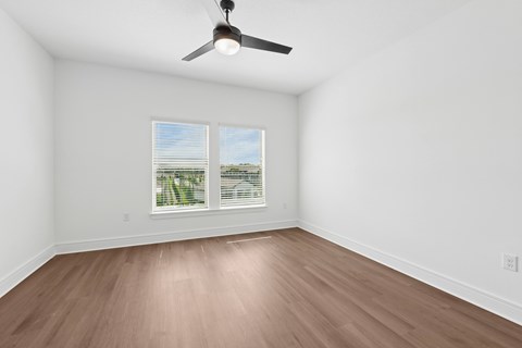 A room with a ceiling fan and a window with blinds.