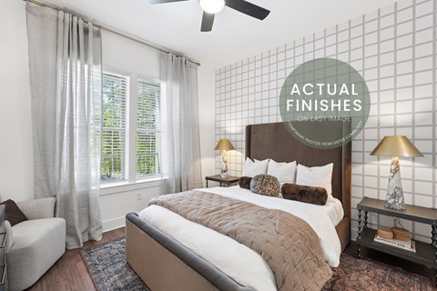 A bedroom with a large bed, a chair, and a ceiling fan.