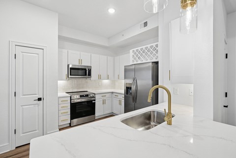 A modern kitchen with a marble countertop and stainless steel appliances.