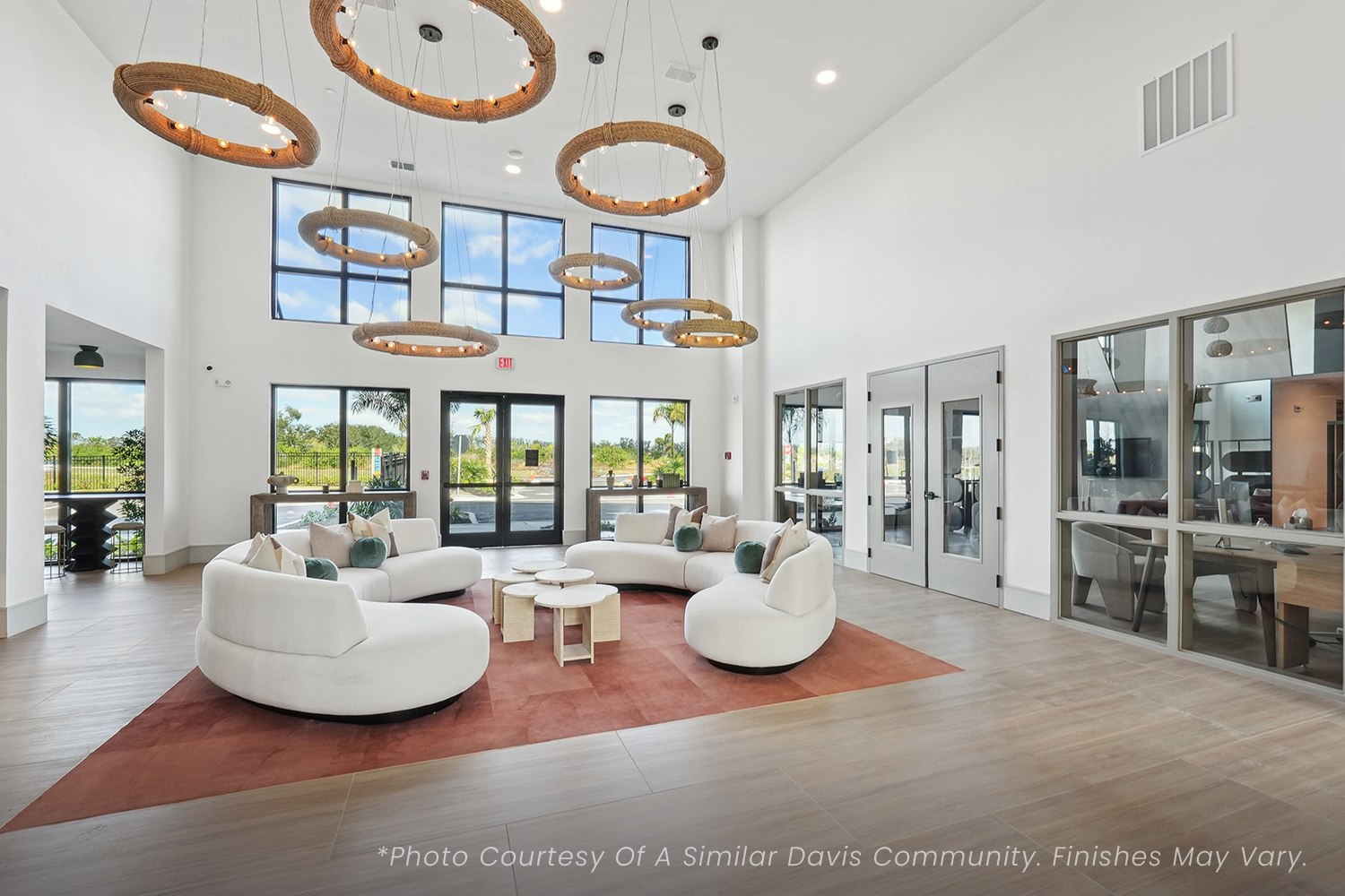 A spacious living room with white furniture and large windows.
