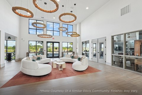 A spacious living room with white furniture and large windows.