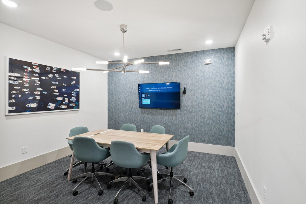 a conference room with a table and chairs and a tv on the wall