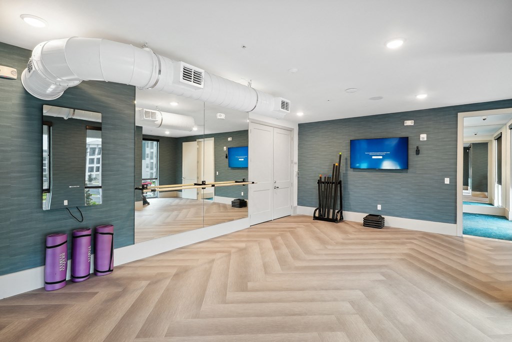 a spacious fitness room with a wood floor and a large mirror