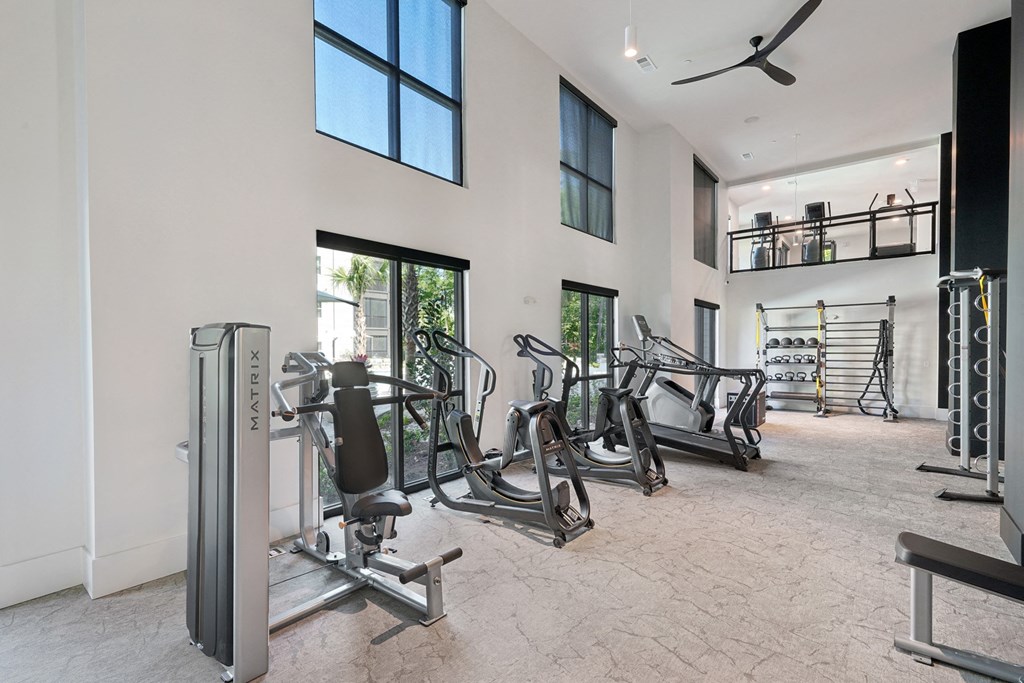 the gym has plenty of exercise equipment and a large window