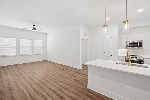 A kitchen with a white countertop and wooden flooring.