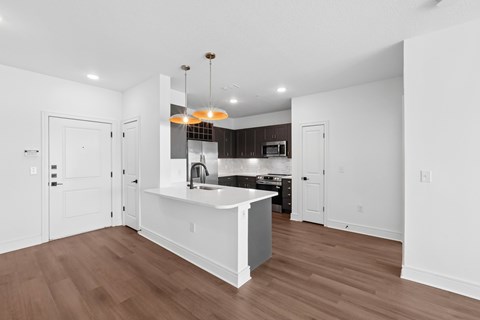 A kitchen with a white island and brown floors.