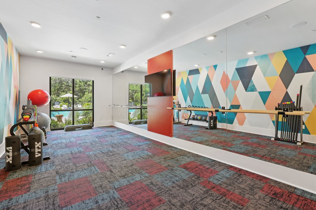 a large room with a gym with weights and a wall with a geometric design