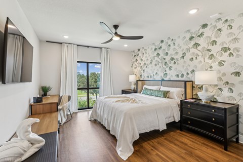A bedroom with two beds, one with a black dresser and the other with a white dresser.