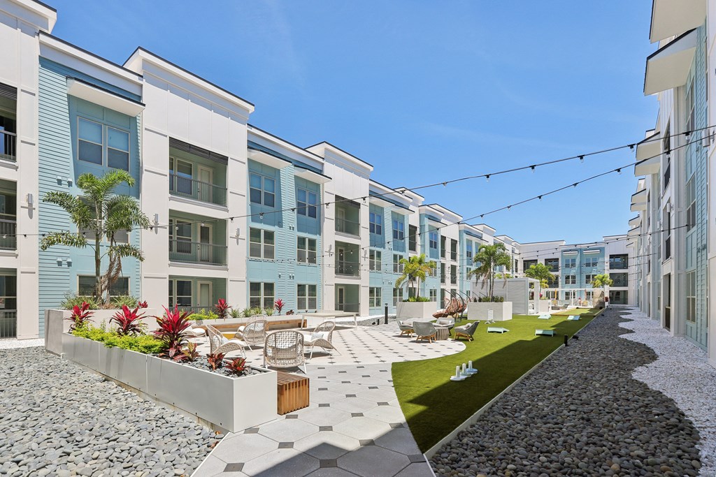 a row of apartment buildings with a courtyard with tables and chairs