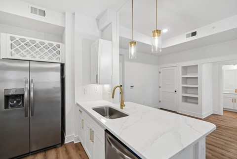 A modern kitchen with a marble countertop and stainless steel appliances.