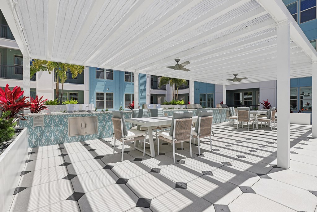 a patio with tables and chairs and a white canopy