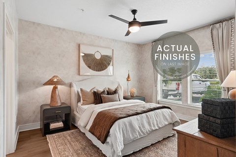 A bedroom with a bed, a lamp, and a fan.