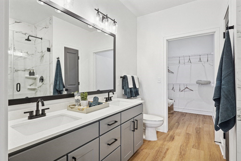 Bathroom with Quartz Countertops, Double Vanity Sinks, Walk-in Shower, and Walk-in Closet