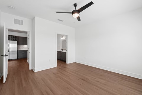 A room with a ceiling fan and wooden floors.