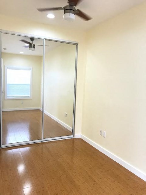 A room with a ceiling fan and sliding glass doors.